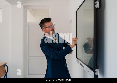 University male teacher giving lecture in the classroom or business man presenter public speaking in a conference meeting room using a display screen Stock Photo
