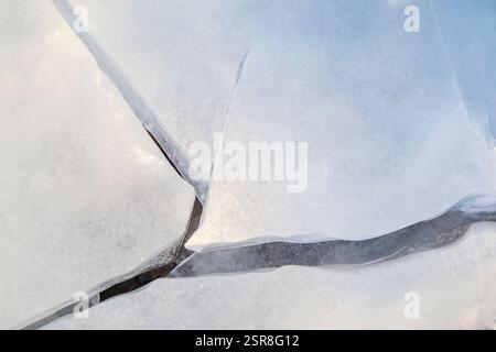 Close-up of cracked ice on a frozen lake in the winter, viewed from above. Abstract background. Copy space, top view. Good for wintry backdrop. Stock Photo