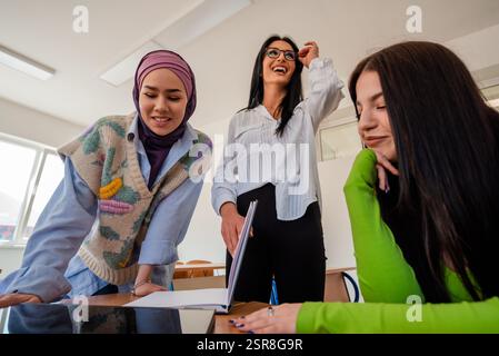 A group of diverse female college students studying together or a young happy business team of three woman working together on a project plan in the Stock Photo