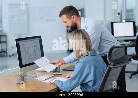 Technicians making digital engineering drawing on computer at desk in office Stock Photo