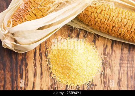 Corn groats and seeds, corncobs on wooden rustic table Stock Photo