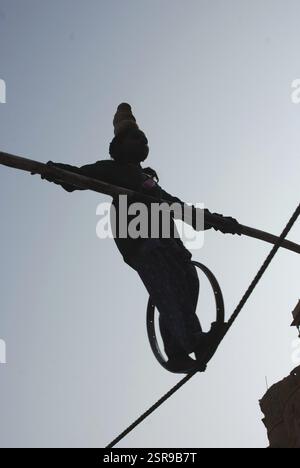Girl balancing with bamboo in hand and stone heap on head on rope ...