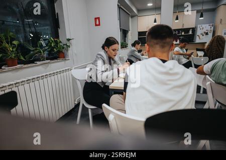 Students enjoying their lunch break in a modern school cafeteria with friends and classmates around. Engaged in lively conversation and relaxing in a Stock Photo