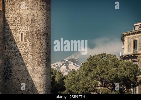 Iconic picture frame of Catania city: Ursino Castle (Castello Ursino); typical residential Art Deco Building, stone pine (Pinus pinea) and the Etna vo Stock Photo