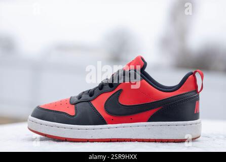 Close-up of stylish red and black nike sneakers placed on a snowy surface, showcasing modern athletic footwear design Stock Photo