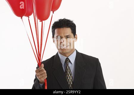 Businessman holding red color gas balloons in one hand MR#703T Stock Photo