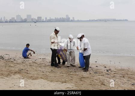 Dabbawalas clean the Chowpatty beach in Mumbai, India on September 16, 2016, and remove the leftover Stock Photo