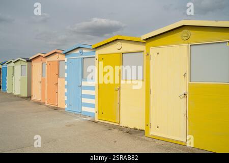 Colorful beach huts (or beach cabins) line the promenade at  Seaford UK.  Brightly painted, they offer seaside charm. Stock Photo
