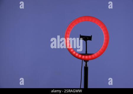 Ring lamp with holder for smartphone against purple background, space for text Stock Photo