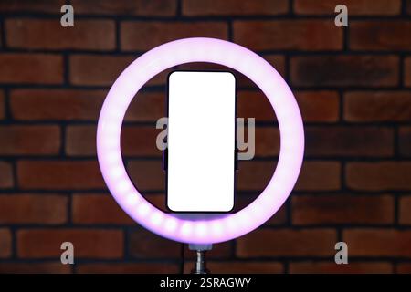 Ring lamp with smartphone against brick wall Stock Photo