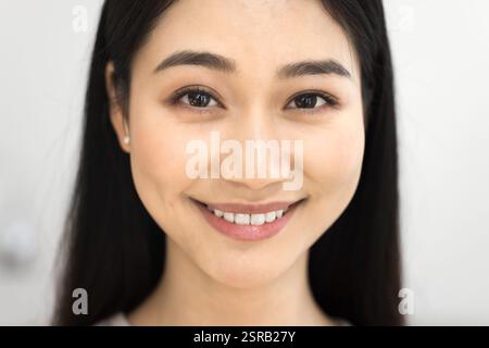 Young 25s Asian woman looking at camera, cropped face view Stock Photo