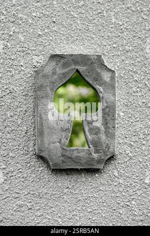 Svetlogorsk, Russia - 13.07.2024 - Unique playing card heart shaped cutout in textured gray wall, revealing glimpse of greenery through opening Stock Photo