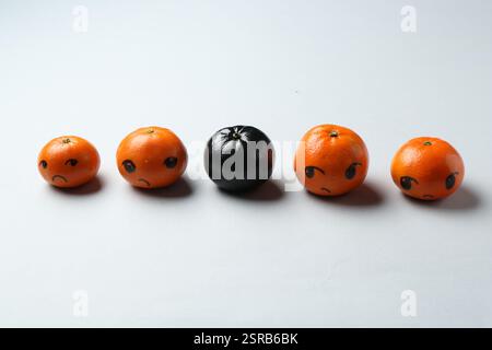 Stop racism. One black tangerine among orange ones on light background Stock Photo