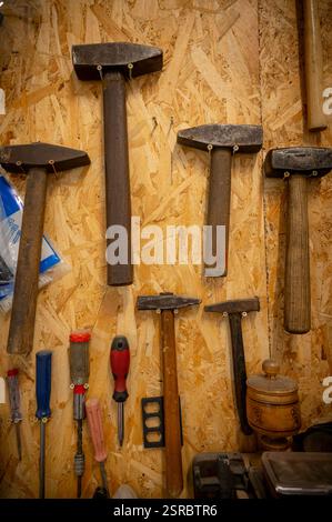 Panel with vintage tools hammers, pliers, saws arranged on a plywood board. Stock Photo