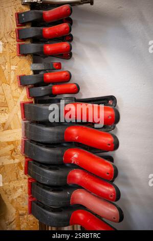 Black plastic clamps with red handles attached to a panel, scene from an art-studio. Stock Photo
