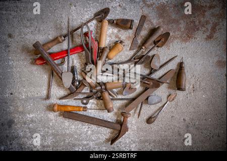 Old shoemaker tools in a pile on the concrete floor. Stock Photo