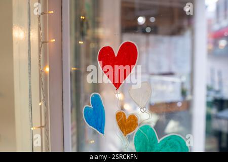 A window with a heart painted on it and a bunch of other hearts. The window is lit up with lights Stock Photo