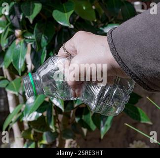 Empty and crumpled plastic bottle with one hand. Stock Photo