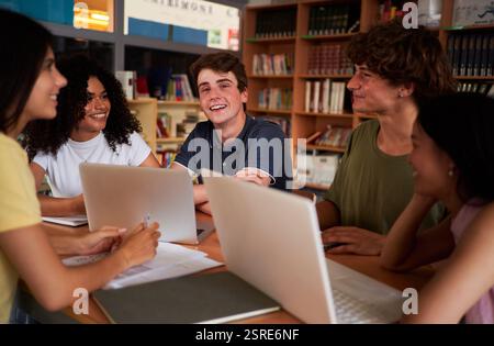 High school students collaborating on project in library using laptops. Stock Photo