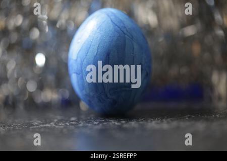 Blue Easter egg chicken egg in front of dark restless bokeh background Stock Photo