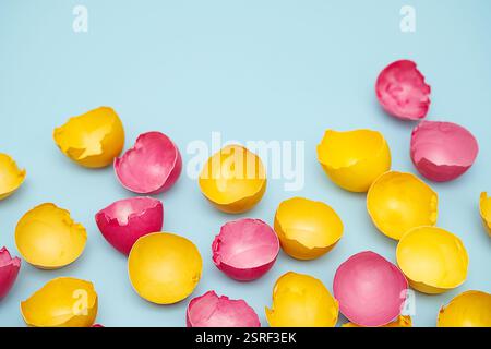 Cracked Yellow and Pink Easter Eggshells on Blue. Flat Lay with Copy Space. Stock Photo
