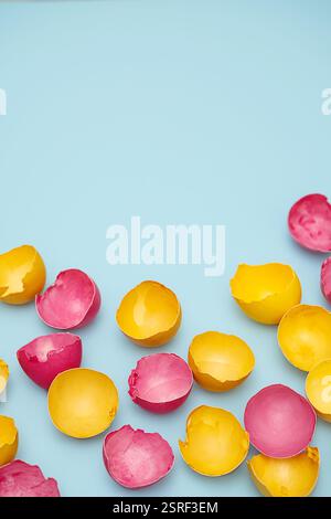 Cracked Yellow and Pink Easter Eggshells on Blue. Flat Lay with Copy Space. Stock Photo