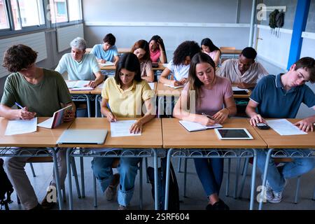 Front view of a group of multiracial students working together in a classroom. Stock Photo
