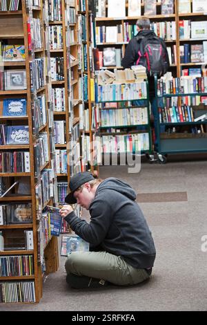 Young man with Down Syndrome reading in secondhand bookshop in Hay on Wye Stock Photo