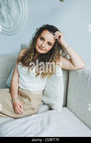 A fashionable young woman poses gracefully in a soft, inviting environment, embodying elegance and charm Stock Photo