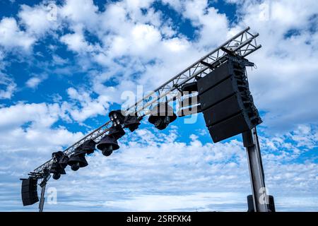 A large set of lights is suspended from a metal pole. The sky is cloudy and the sun is shining through the clouds Stock Photo
