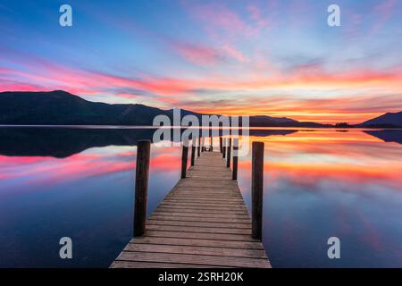 Romantic sunset over wooden jetty with reflections on a summer evening in The Lake District, UK. Stock Photo