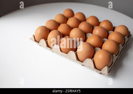 Chicken eggs in a paper tray lying on the table Stock Photo
