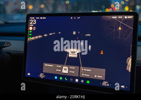 Close up view of Tesla autopilot screen displaying navigation and road objects at night. Stock Photo