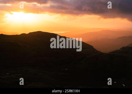 Golden morning light breaking through dramatic clouds over mountains of The Lake District, UK. Stock Photo