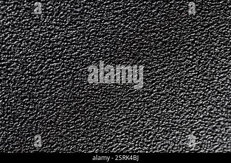 Black grainy plastic surface background with bump close up view Stock Photo