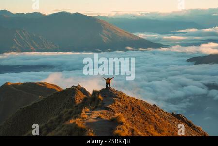 Asian couple standing and embracing on summit of Roys Peak, surrounded by foggy in the morning at New Zealand Stock Photo