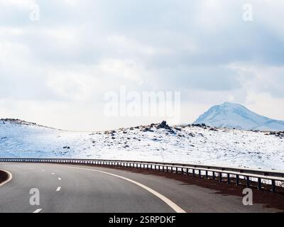 turn of M1 North-South highway in mountais of Aragatsotn Province of Armenia on cloudy winter day (view through car windshield) Stock Photo