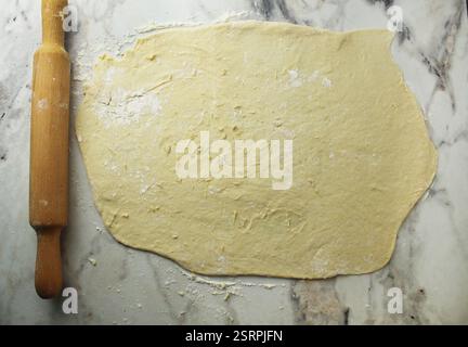 Rolled out layer of yeast dough on a table with flour. Stock Photo