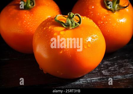 orange tomato on black wood background wet Stock Photo