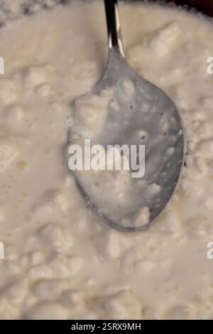 cottage cheese made from milk with cream close-up, grainy cottage cheese with cream on the table with a spoon Stock Photo
