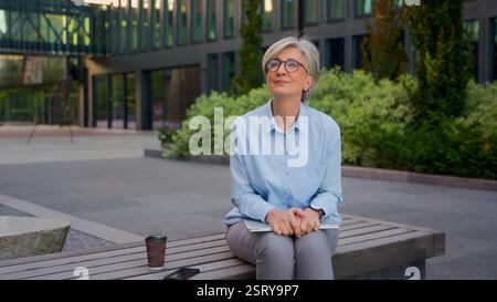 Mature woman working outside old business lady in eyeglasses hold laptop pc smiling senior businesswoman in city modern urban street downtown female Stock Photo