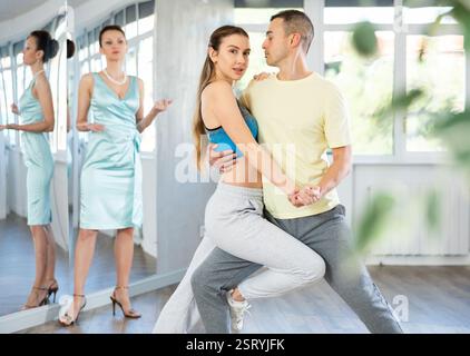 Couple practicing passionate tango guided by female dance instructor in studio Stock Photo