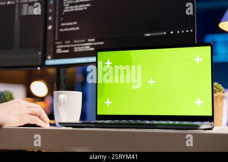 System administrator designing and developing software applications using green screen laptop. Tech support expert implementing and maintaining company systems using chroma key device Stock Photo