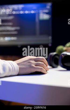 Teleworking IT admin working from RGB lit home, testing and deploying programs and systems. Close up of software technician checking code displayed on computer screens in apartment Stock Photo