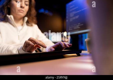 Teleworking programmer doing software debugging, checking flaws in lines of code displayed on PC monitors. IT admin in apartment fixing coding issues, typing on PC keyboard Stock Photo