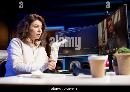 Developer doing software debugging helped by coworker in videocall, checking errors in lines of code. Woman working from home fixing coding mistakes, assisted by colleague in teleconference Stock Photo