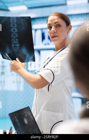 Doctor showing the x ray scan results to her colleagues in a meeting, people with expertise collaborating on treatment options based on diagnostic. Disease prevention strategies with radiography. Stock Photo