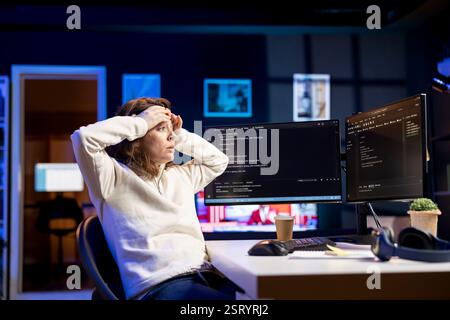 Programmer suffering from headache while filtering malicious traffic from cybercriminals attempting to steal company data. Stressed woman hurting from pain and overworking, preventing malware Stock Photo