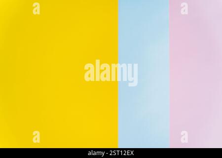 Minimalist abstract background featuring vertical strips of yellow, blue, and pink paper. Modern and colorful composition suitable for design, brandin Stock Photo