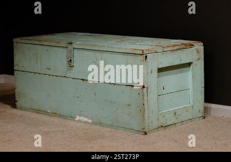 An old green army trunk sitting in the corner of a room Stock Photo